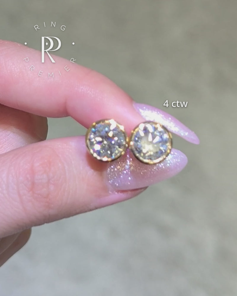 Solane Round Cut 4 carat (4 ct tw) lab-grown diamond bezel stud earrings in yellow gold, shown held in hand