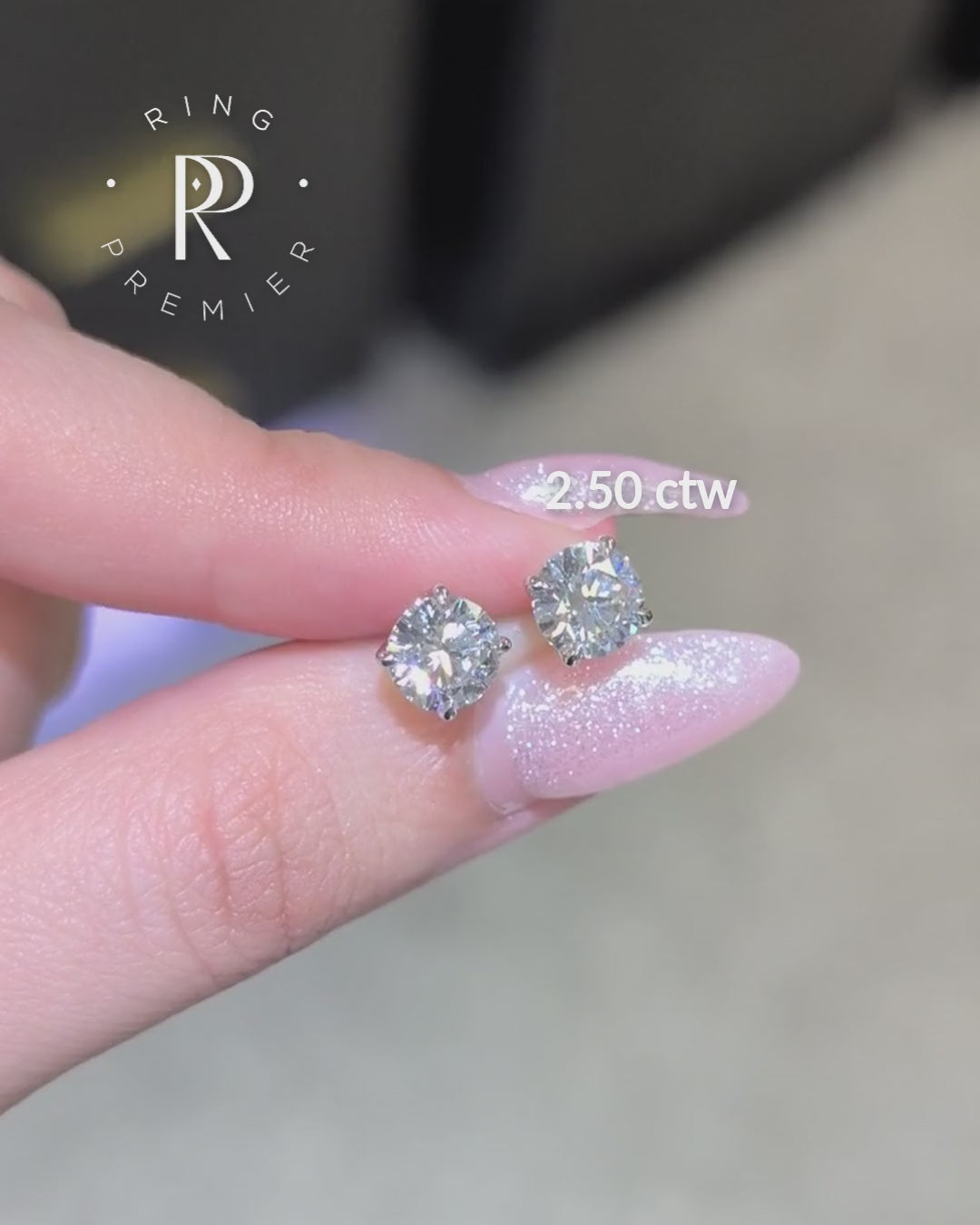 Geneva 4-prong basket round lab-grown diamond stud earrings, 2.50 ct tw pair in white gold shown held in hand