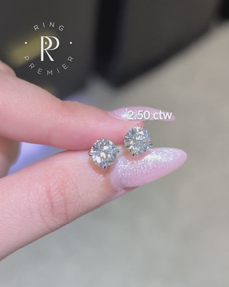 Geneva 4-prong basket round lab-grown diamond stud earrings, 2.50 ct tw pair in white gold shown held in hand