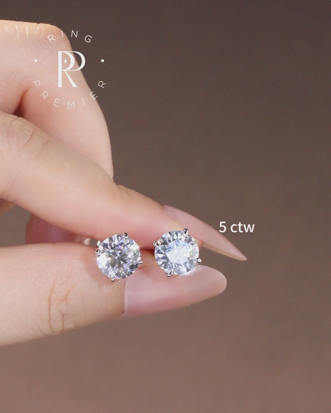 Geneva 5 carat (5 ct tw) round lab-grown diamond stud earrings in a 4-prong basket setting, shown held in hand