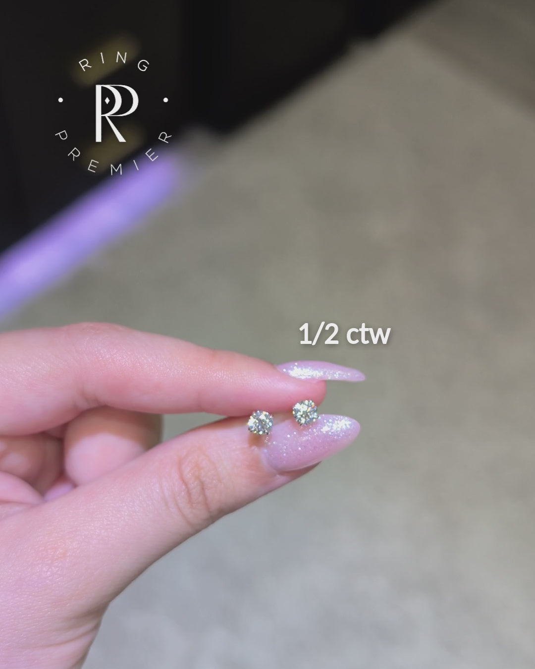 Geneva 1/2 carat (1/2 ct tw) round lab-grown diamond stud earrings in a white gold 4-prong basket setting, shown held in hand