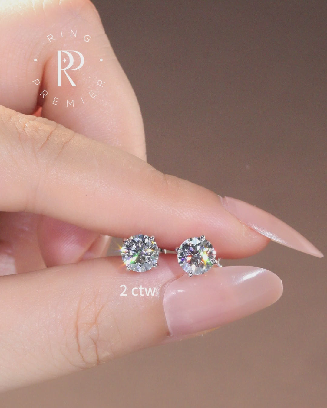 Geneva 2 carat (2 ct tw) round lab-grown diamond stud earrings in a 4-prong basket setting, shown held in hand
