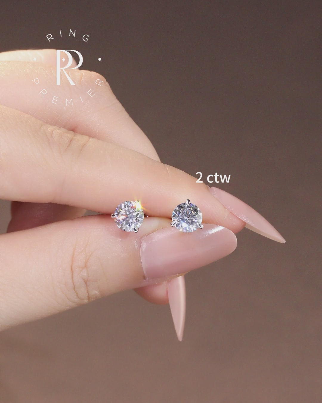 Florence 2 carat (2 ct tw) round lab-grown diamond stud earrings in a 3-prong martini setting, shown held in hand