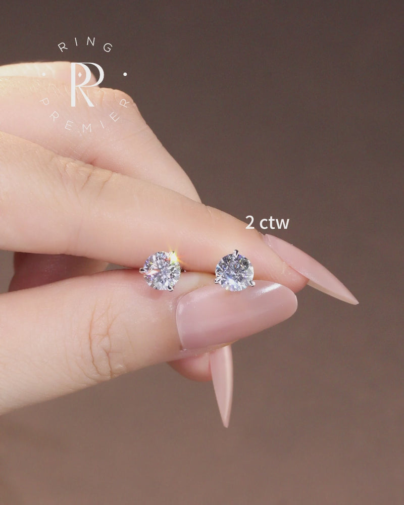 Florence 2 carat (2 ct tw) round lab-grown diamond stud earrings in a 3-prong martini setting, shown held in hand
